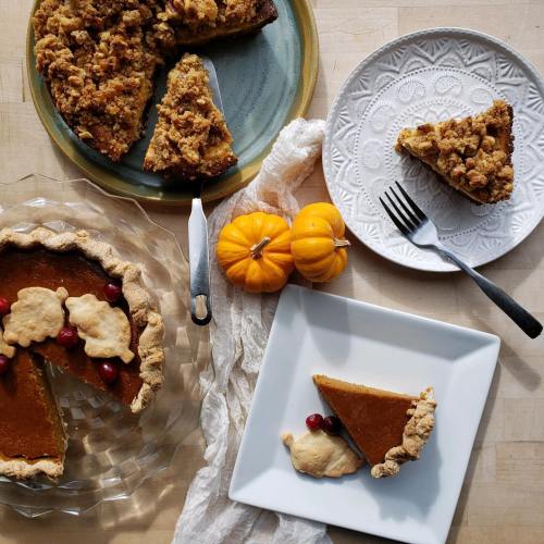 A table with pumpkin pie slices, mini pumpkins, and a fork on a plate, showcasing a cozy autumn dessert scene.