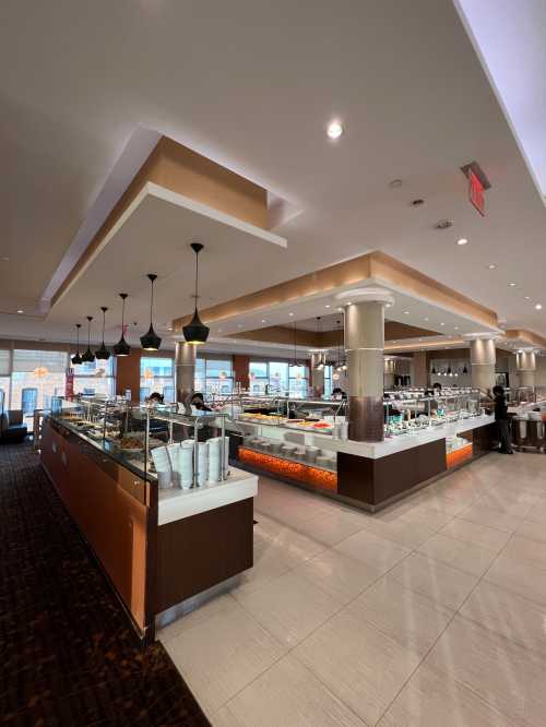 A modern restaurant interior featuring a buffet area with various food displays and stylish lighting.