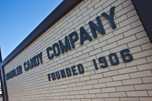 Sign for Spangler Candy Company, established in 1906, displayed on a brick wall.