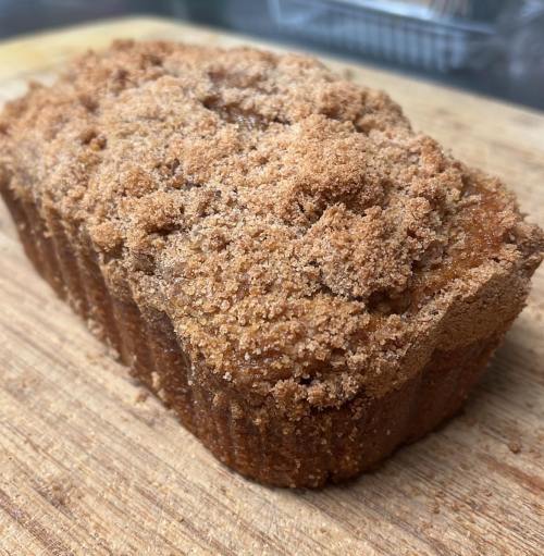 A freshly baked loaf of cinnamon streusel bread on a wooden cutting board.