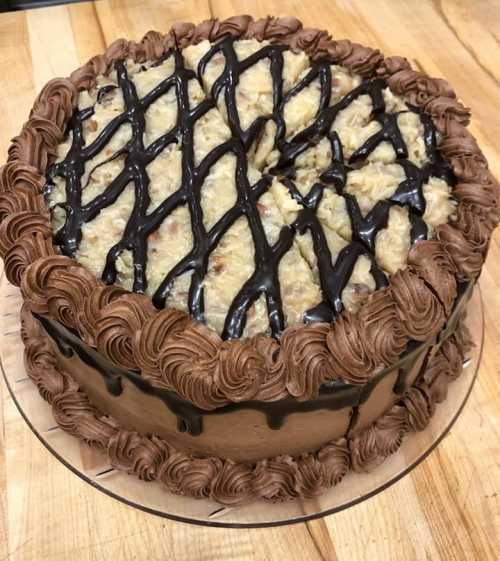 A chocolate cake with a textured topping, drizzled with chocolate and decorated with chocolate frosting on the sides.