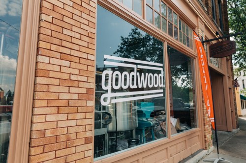 Exterior view of a brick building featuring a large window with the "goodwood" logo displayed prominently.