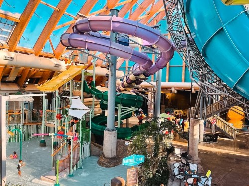 Colorful water slides and attractions in a vibrant indoor water park, with visitors enjoying the fun.
