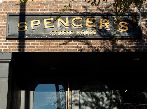 Sign for Spencer's Coffee House on a brick wall, featuring gold lettering against a dark background.