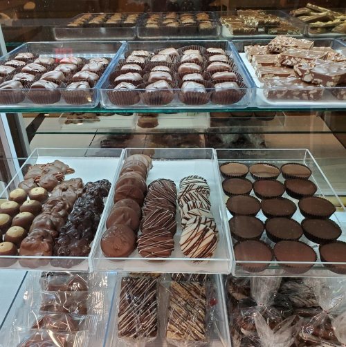 A display case filled with various chocolate confections, including truffles, bars, and coated treats.