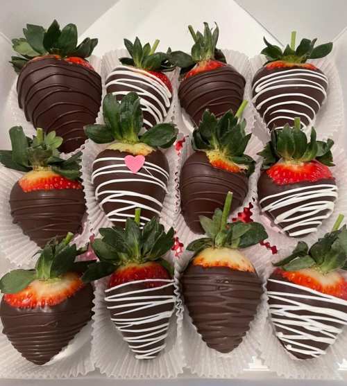 A box of 12 chocolate-covered strawberries, decorated with white drizzle and a small pink heart.