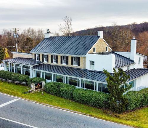 Aerial view of a two-story restaurant with a metal roof, surrounded by greenery and located near a road.