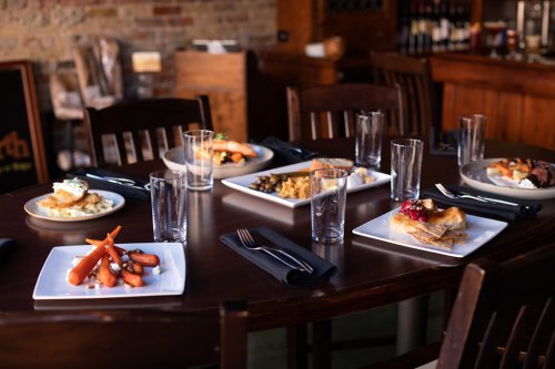 A dining table set with various dishes and empty glasses, showcasing a variety of colorful meals.