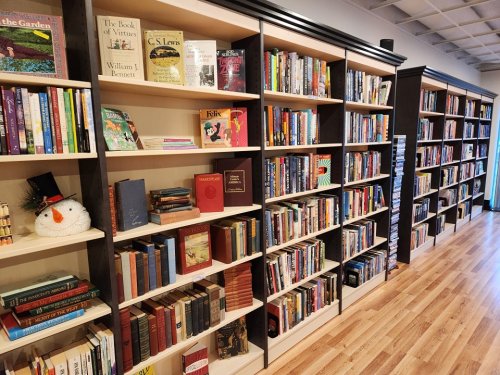 A cozy bookstore interior with shelves filled with various books and a snowman decoration on a shelf.