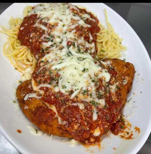 A plate of chicken parmesan topped with marinara sauce and melted cheese, served over a bed of spaghetti.