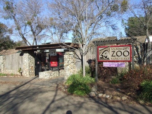 Entrance to Folsom City Zoo Sanctuary, featuring a stone wall and a sign with the zoo's name and logo.