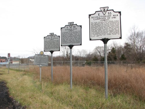 Three historical markers along a grassy area, detailing events from the Revolutionary War and local history.