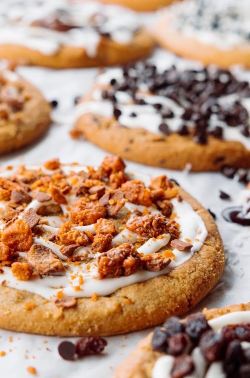 Close-up of decorated cookies with frosting and various toppings, including chocolate chips and crushed candy.
