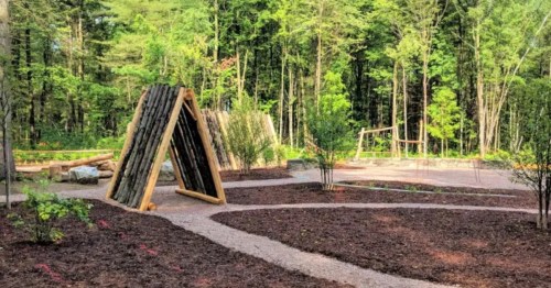 nature-themed playground in vermont with a paved trail and several green trees