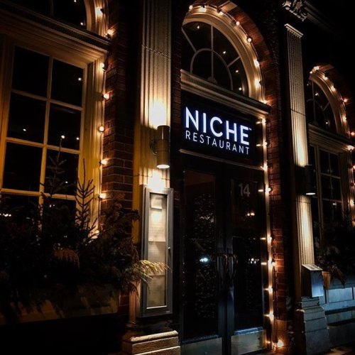 Exterior of Niche Restaurant at night, featuring warm lights and a welcoming entrance.