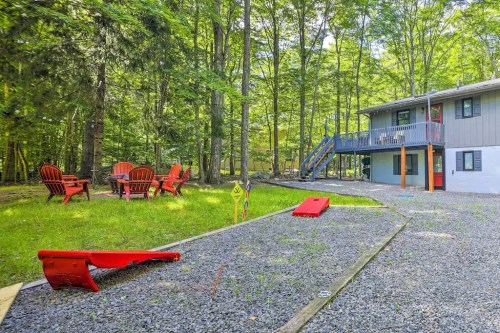 A backyard with red chairs, a gravel path, and a house surrounded by trees.