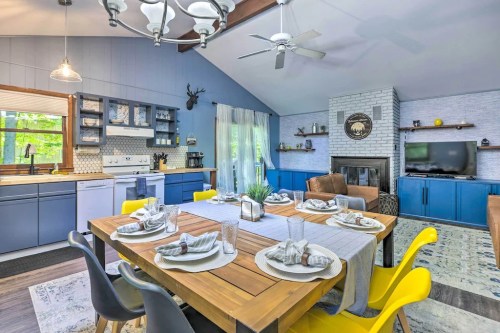 Bright kitchen and dining area with a wooden table set for dinner, blue cabinets, and a cozy fireplace.