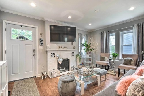 Cozy living room with a fireplace, TV, and stylish decor, featuring a light color palette and comfortable seating.