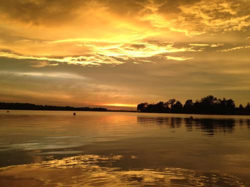 A serene sunset over a calm lake, with vibrant orange and yellow hues reflecting on the water's surface.