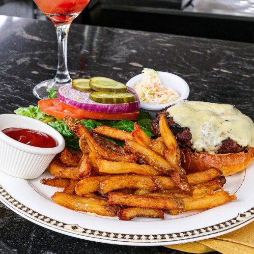 A juicy cheeseburger with lettuce, tomato, pickles, and onion, served with crispy fries and a side of ketchup.