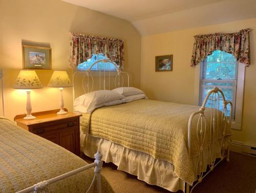 Cozy bedroom with two beds, yellow bedding, floral curtains, and warm lighting from bedside lamps.