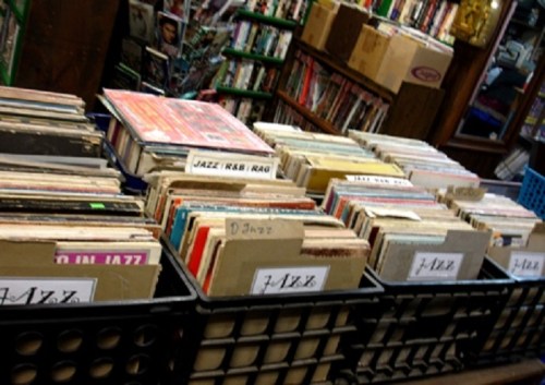 A collection of vinyl records organized in bins, featuring various genres, including jazz, in a cozy store setting.