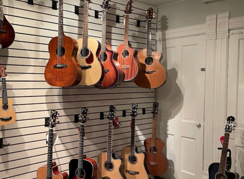 A wall display of various acoustic guitars hanging on hooks, showcasing different shapes and wood finishes.