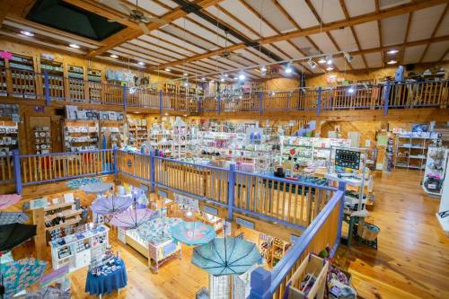 A spacious craft store with wooden beams, multiple levels, and various handmade items displayed throughout.