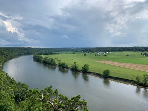 A scenic view of a river winding through lush green fields under a cloudy sky.