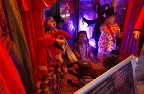 A spooky funhouse scene with creepy dolls, clowns, and eerie lighting, creating a Halloween atmosphere.