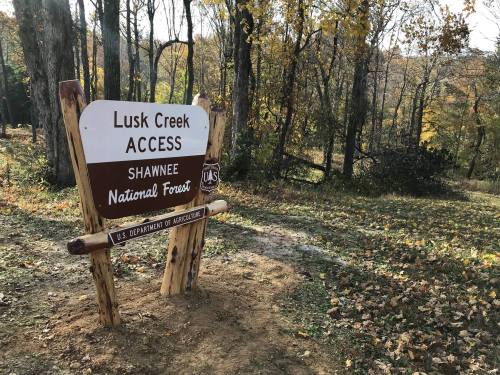 Sign for Lusk Creek Access in Shawnee National Forest, surrounded by trees and autumn foliage.
