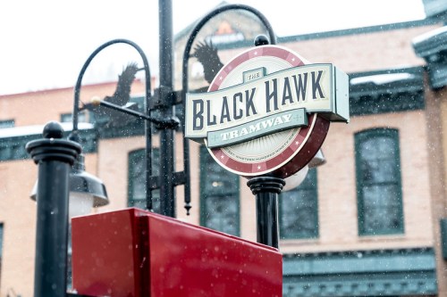 Sign for the Black Hawk Tramway, featuring a vintage design, with snow falling in the background.