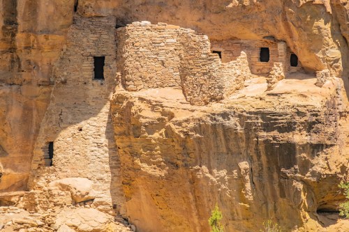 Ancient stone ruins built into a rocky cliff, featuring small windows and a weathered exterior.