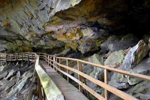 A wooden walkway leads through a rocky cave with colorful stone formations above.