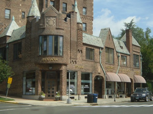 Historic brick building with pointed roofs, large windows, and awnings, featuring shops on the ground floor.
