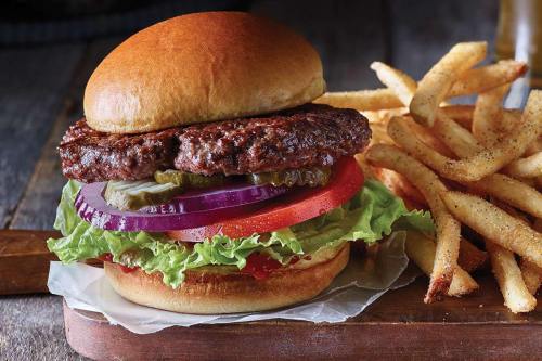 A juicy hamburger with lettuce, tomato, onion, and pickles, served with a side of crispy French fries.