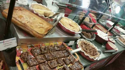 A display of various desserts, including brownies, pies, and cakes, in red and white serving dishes.