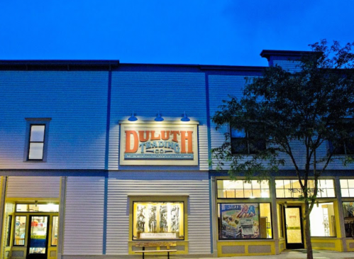 A building exterior at dusk featuring a sign that reads "Duluth" and large windows with displays.