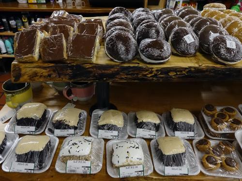 A display of various baked goods, including chocolate cakes and pastries, arranged on wooden shelves.