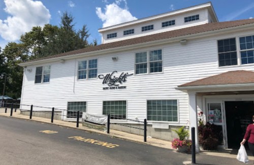 Exterior of Wright's Meat Farm & Market, a white building with large windows and a sign, on a sunny day.