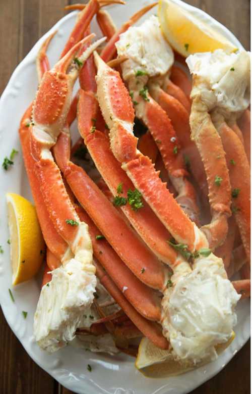 A platter of steamed crab legs garnished with parsley and lemon wedges.