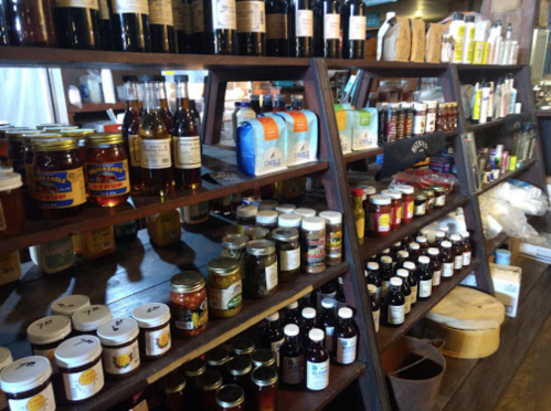 Shelves filled with various jars, bottles, and packages of food products, including jams, sauces, and spices.