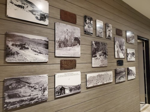 A wall display featuring historical black-and-white photographs and plaques depicting a mining area and its history.
