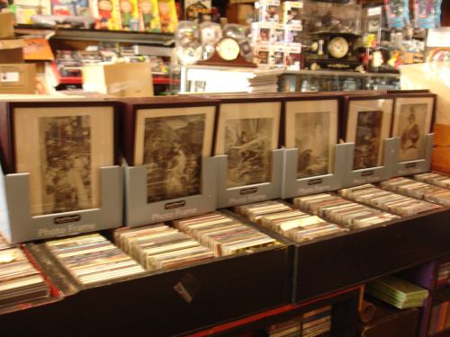 A display of framed photos on a table, surrounded by stacks of CDs in a cluttered shop.