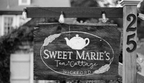 A wooden sign for "Sweet Marie's Tea Cottage" in Wickford, featuring a teapot illustration and decorative leaves.
