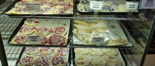 A display case filled with various pastries, including cheese danishes and fruit-topped options.