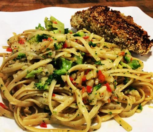 A plate of pasta with broccoli and red peppers, served with a crispy, breaded piece of chicken on the side.