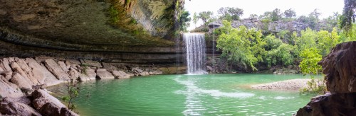 A serene waterfall cascades into a turquoise pool, surrounded by lush greenery and rocky cliffs.
