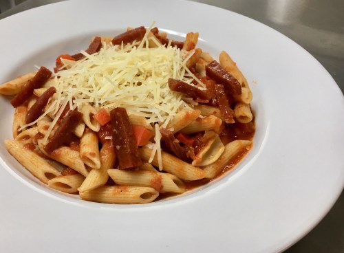 A plate of penne pasta topped with marinara sauce, diced peppers, and a generous sprinkle of grated cheese.