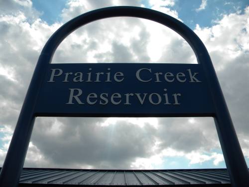 Sign for Prairie Creek Reservoir against a cloudy sky.